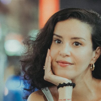 Portrait d’Amelle Zaïd, souriante, le menton dans la main.